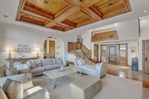 Un'ampia zona giorno con soffitto alto, una scala e vista sull'esterno.