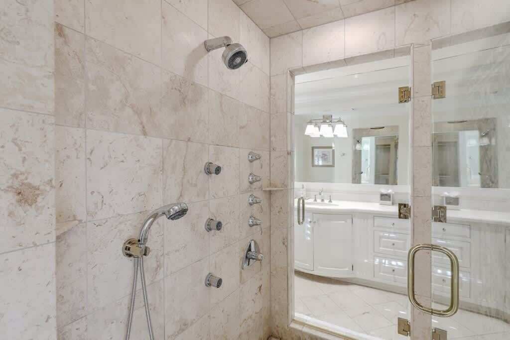 Un baño con ducha, espejo y lavabo.