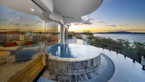Piscina infinita moderna con jacuzzi, con vistas a un paisaje marino.