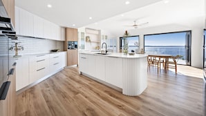 Una cocina moderna con armarios blancos, una isla central y un comedor con vistas.