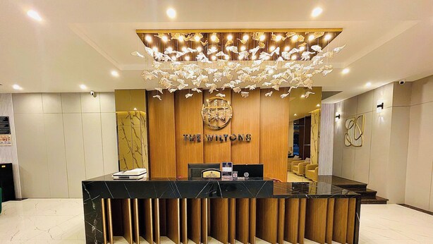 A reception desk with a wooden backdrop and a chandelier. - THE WILTONS HOTEL LAO CAI (Lao Cai)