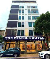 Un hotel con una fachada moderna, destacando un cartel grande que dice "The Wiltons Hotel" y una entrada visible con puertas de cristal.