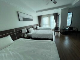 Habitación de hotel con dos camas, un ventilador de techo, una mesita pequeña y una silla.