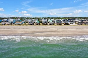 En fastighet vid stranden med flera hus och en sandstrand.