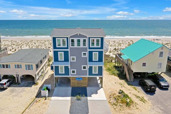 Una propiedad frente a la playa con un edificio central y dos construcciones laterales, con vista al mar.