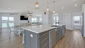 A spacious kitchen with a large island, modern appliances, and pendant lighting. - BonBini: Oceanfront 7-bedroom house in Oak Island, perfect for large groups. (Oak Island)