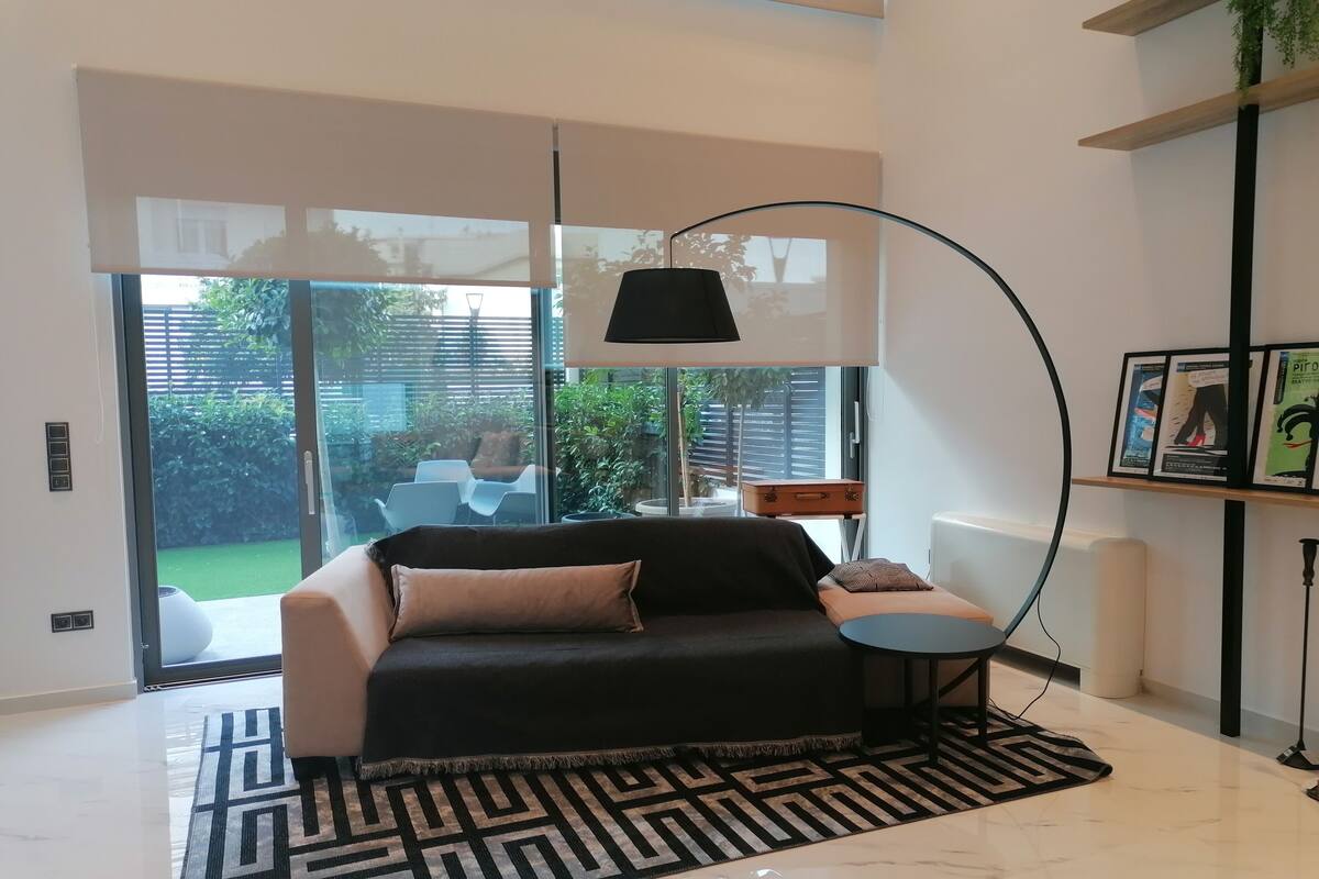 A modern living room with a sofa, a patterned rug, a floor lamp, and a view of the outdoors.