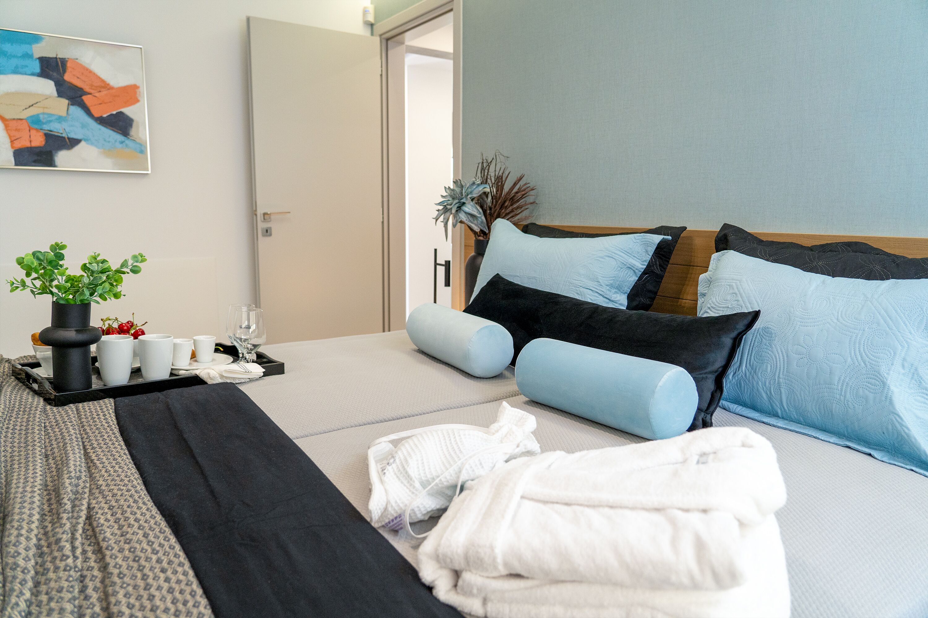 Habitació d'hotel ben organitzada amb un llit, una taula de nit i una planta en test.