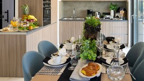 Cocina moderna con armarios de madera, una mesa de comedor para cuatro personas con platos, vasos y un centro de mesa con plantas.