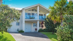 Een woonhuis met twee verdiepingen, een balkon, een garagepoort en een verzorgd gazon.
