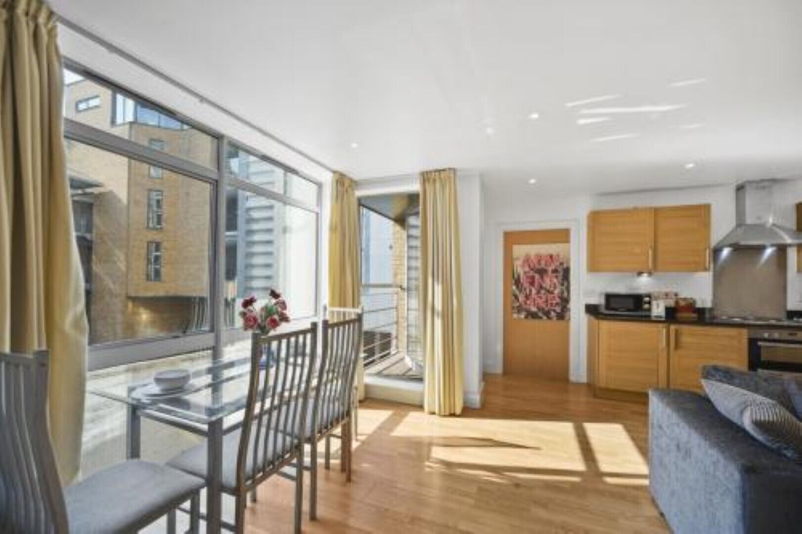 A modern apartment with a dining area, kitchen, and large windows.