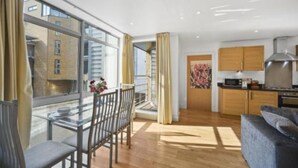 Ein modernes Apartment mit Essbereich, Küche und großen Fenstern.