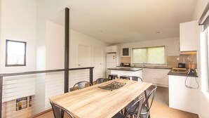 A modern kitchen with white cabinets, a wooden dining table, and a small island with a sink. - 25 A Twynam Street, Jindabyne (Jindabyne)
