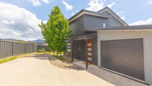 A modern two-story house with a garage, a driveway, and a fenced backyard. - 25 A Twynam Street, Jindabyne (Jindabyne)