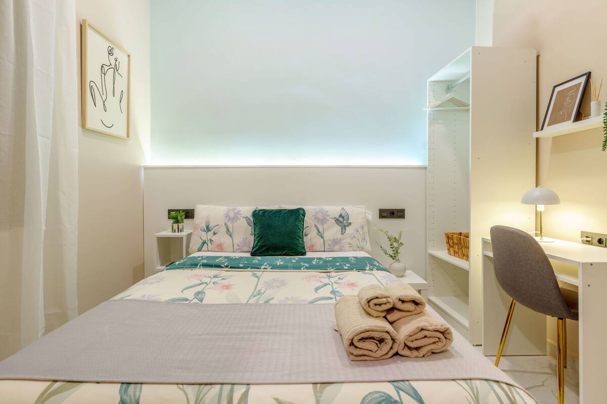 Une chambre bien rangée, avec un lit, des tables de chevet, un bureau et une chaise.