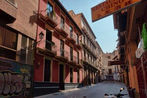 Una calle estrecha con edificios que tienen balcones y un letrero de restaurante.