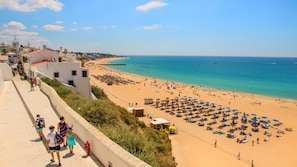 Una playa costera con un paseo pavimentado y sombrillas.