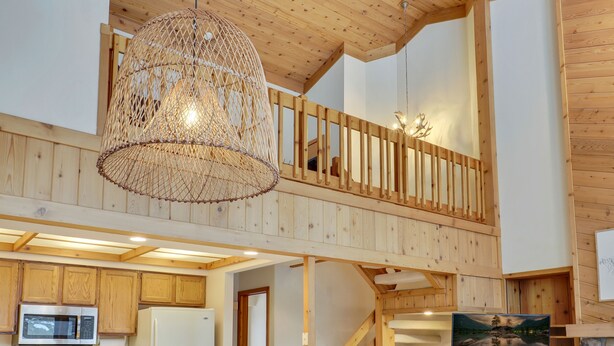 A wooden interior with a kitchen, a staircase, and a hanging light fixture. - Hamlet Village Chalet at Nubs Nob/ 4 bedrooms sleeps 12 (Harbor Springs)