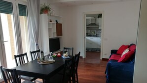 A dining area with a black table and chairs, a TV, and a kitchen in the background. - Two Steps from the Lake (Colico)