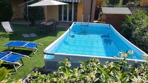 A rectangular swimming pool with a ladder, surrounded by green artificial grass and blue lounge chairs. - Two Steps from the Lake (Colico)