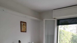 A bedroom with a bed, a bedside table, a window, and a view of the outdoors. - Two Steps from the Lake (Colico)