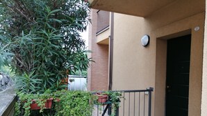 A small outdoor area with potted plants, a metal gate, and a building entrance. - Two Steps from the Lake (Colico)