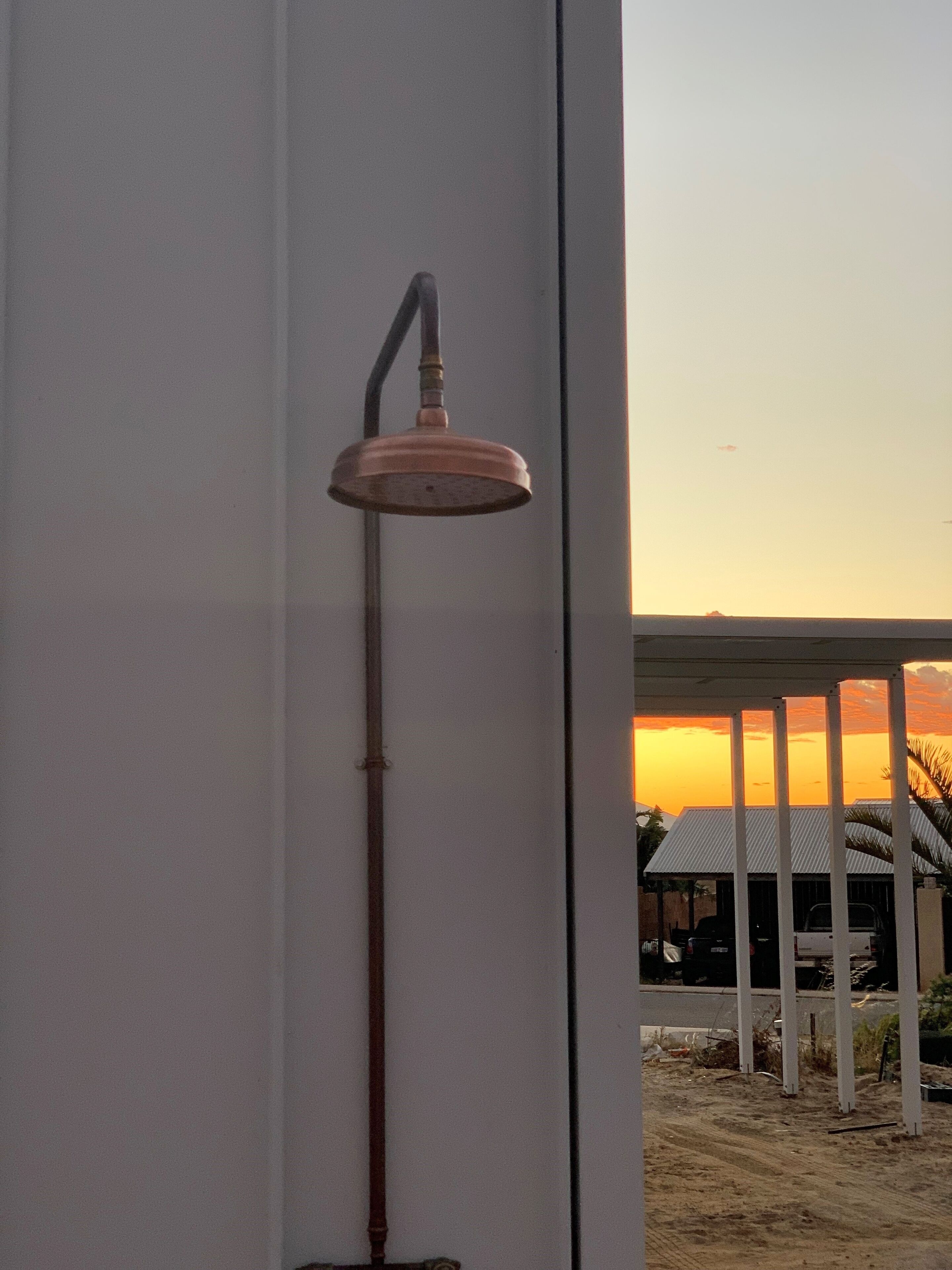 Un vàter de dutxa fixat a la paret, amb una vista del capvespre i un edifici al fons.