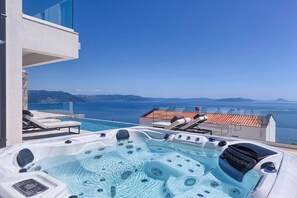 A hot tub with a clear view of the sea and mountains in the background.