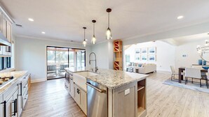 Una cocina amplia con una isla grande, armarios de madera e iluminación colgante.