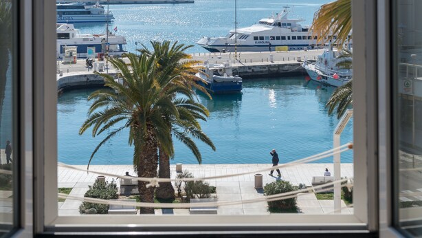 Un puerto deportivo con barcos amarrados, un faro y palmeras.