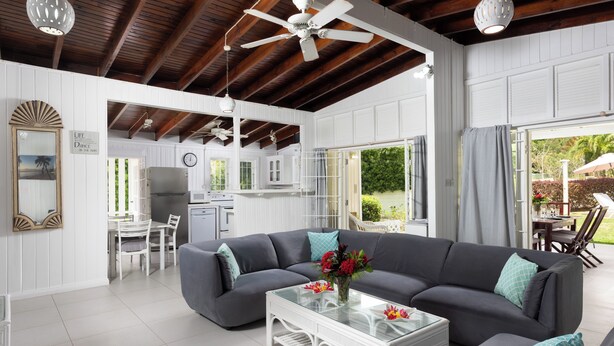A spacious living area with a gray sofa, white coffee table, and a ceiling fan.