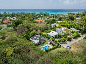 Une vue aérienne d’un quartier résidentiel avec des maisons, une piscine et une vue sur l’océan.
