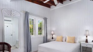 A bedroom with a large bed, two bedside tables with lamps, a chair, and a mirror.