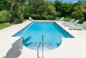 Una piscina al aire libre, tumbonas