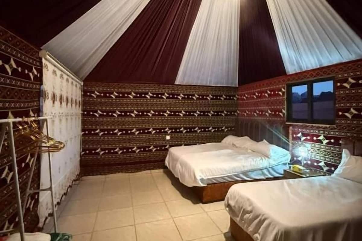 Una habitació amb dos llits, un armari i un mirall.
