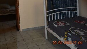 Een stapelbed met een roze en blauwe matras, een airconditioner aan de muur en een betegelde vloer.