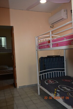 Ein Etagenbett mit einer rosa und blauen Matratze, eine Klimaanlage an der Wand und ein gefliester Boden.