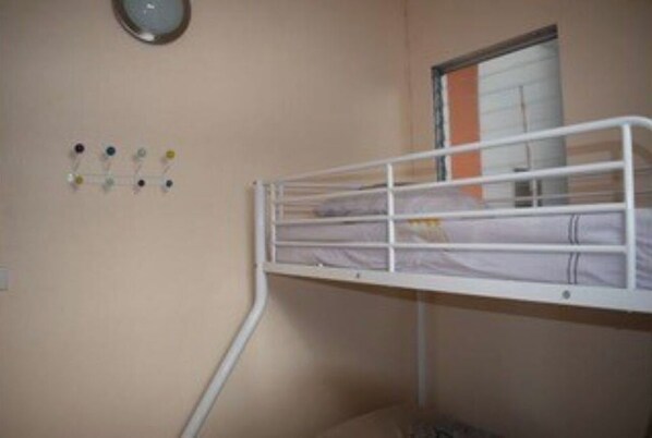 A bunk bed in a room with a window, a wall clock, and a set of colorful push pins. - La Perle Bleue (Le Moule)