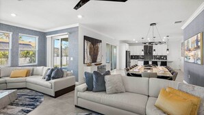 A modern living room with a sectional sofa, a dining area, and a kitchen.