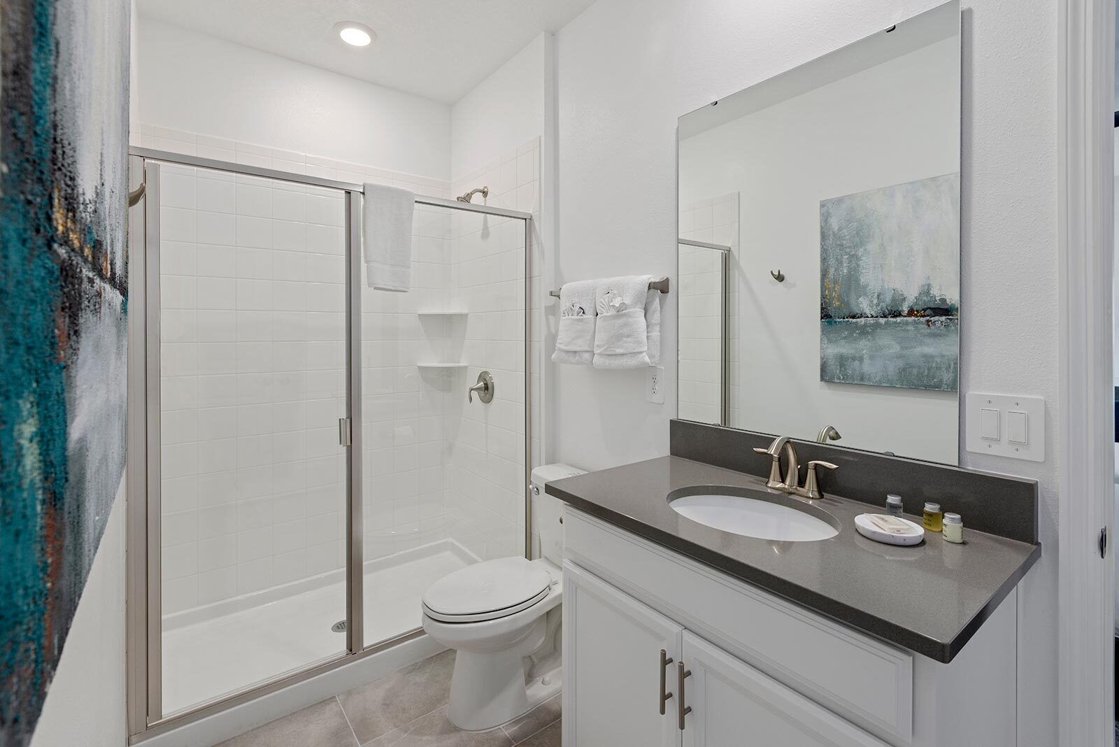 Une salle de bain moderne avec une douche à parois de verre, des toilettes blanches et un meuble-lavabo avec un évier et un miroir.