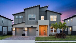 A modern two-story residential building with a garage, a well-maintained lawn, and a street view. - Rhythmic Retreat | Beach + music lover's oasis w pool, movie theater, karaoke rm (Melbourne Beach)