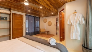 Un dormitorio con techo de madera, una cama con manta gris, una bata de baño blanca y una puerta de madera.