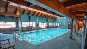 Piscina interna con soffitto in legno e vista sull'esterno.