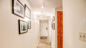 Un corridoio con quadri appesi alle pareti, una porta in legno e un pavimento piastrellato.
