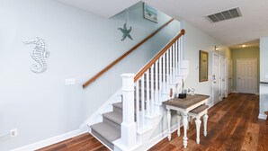 A staircase with white railings and a wooden handrail, leading to a landing with a wooden table and bench. - 2nd Row, 4 BR Beach House with Community Pool! Endless Summer Nights (Surfside Beach)