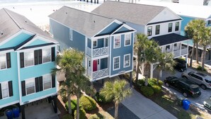 A coastal residential area with houses featuring balconies and a pier extending into the ocean.