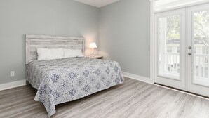 A bedroom with a bed, nightstand, and a door leading to a balcony.