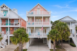 A beachfront property with a two-story building, a covered walkway, and a flag.