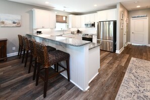 A modern kitchen with white cabinets, a granite countertop, and stainless steel appliances. - 5 BR Beach House with Private Pool in Surfside Beach! The Pink Flamingo (Surfside Beach)