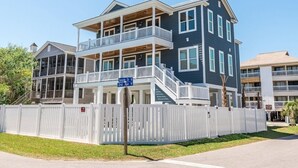 A multi-story residential building with balconies, a covered front porch, and a gated entrance. - Ocean View 7 BR Beach House with a Private Pool! Seaside Retreat  (Surfside Beach)
